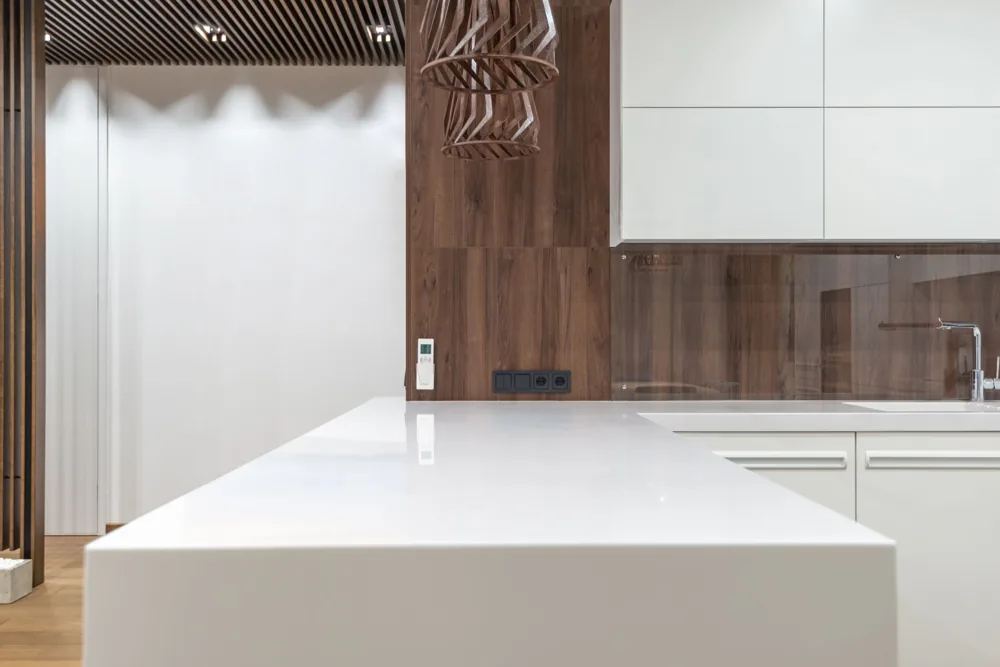 Illustrative white kitchen worktop with a broad preparation surface and wood cabinetry beyond