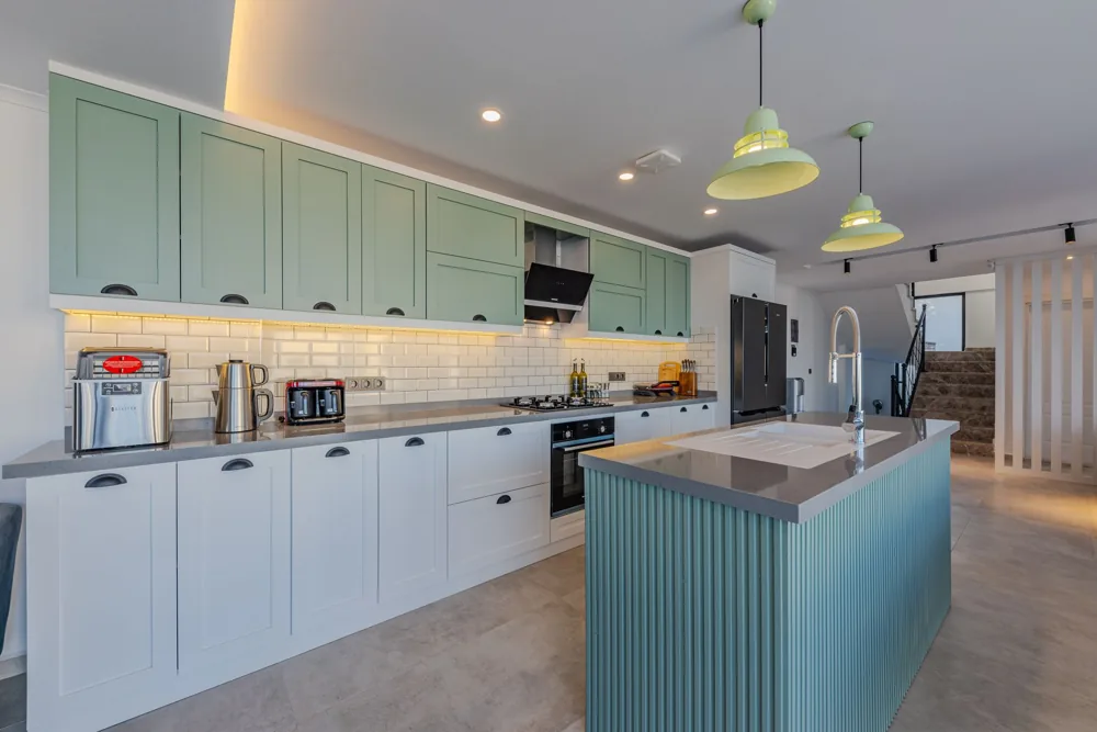 Illustrative sage green and white kitchen with an island and pendant lighting