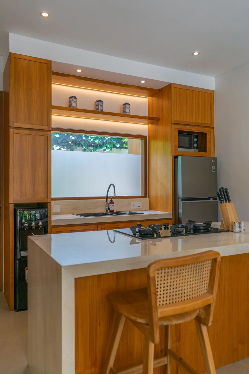 Illustrative warm timber kitchen with fitted cabinets, a pale island worktop and open shelving